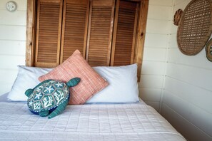 Un lit avec une couverture à motifs, un oreiller et un coussin en forme de tortue.