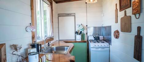 A compact kitchen with a gas stove, a sink, and wooden countertops.