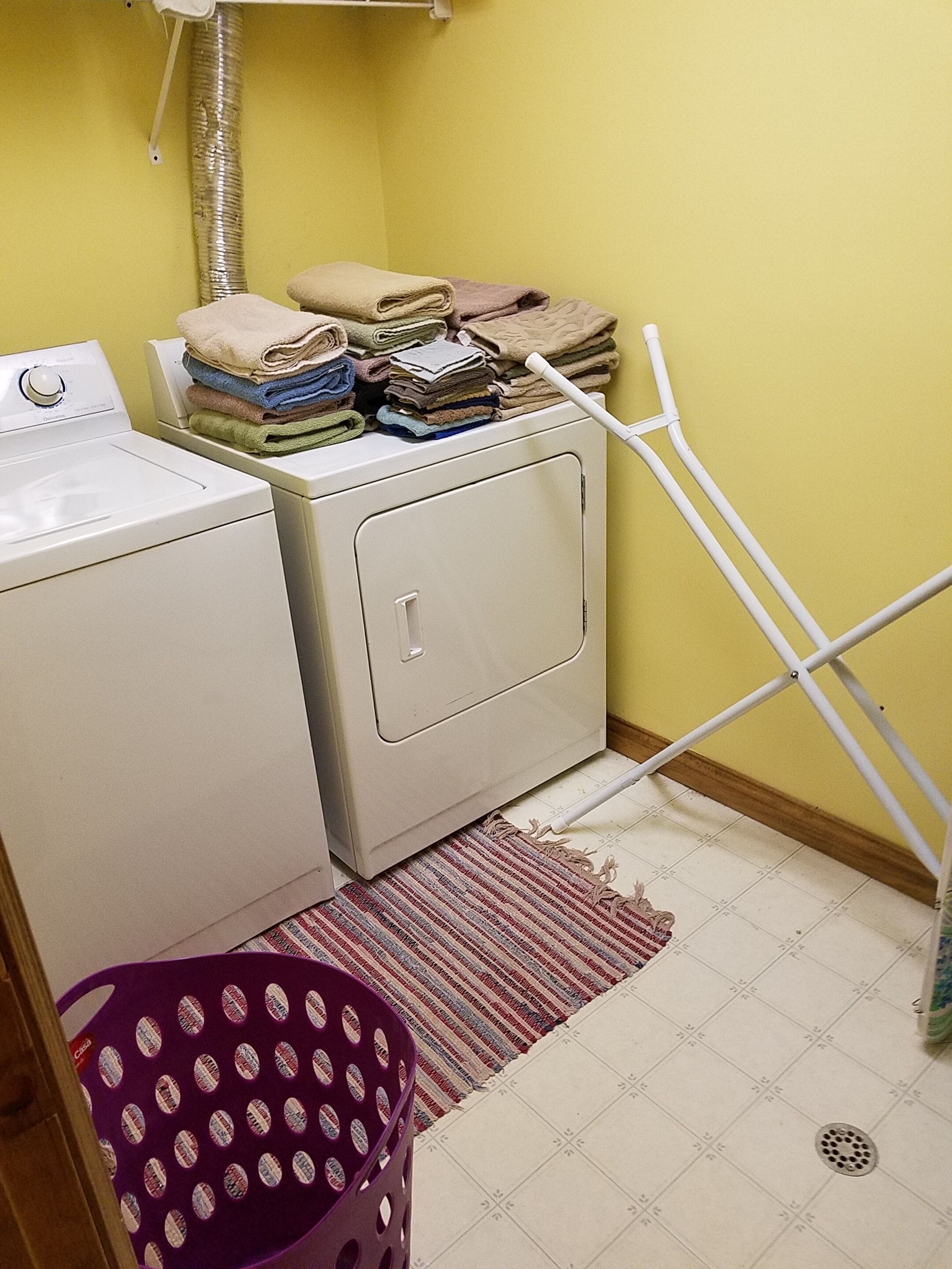 Un espace buanderie comprenant un lave-linge, un sèche-linge et des piles de serviettes.