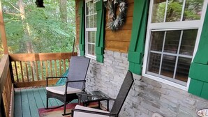 A porch with two rocking chairs, a welcome sign, and a bucket with items. - Cozy Cabin Located in gated resort near Lake Cumberland. Pool & boat ramp onsite (Burnside)
