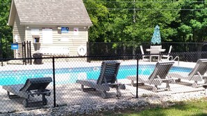 A swimming pool area with lounge chairs and a small building with a sign. - Cozy Cabin Located in gated resort near Lake Cumberland. Pool & boat ramp onsite (Burnside)