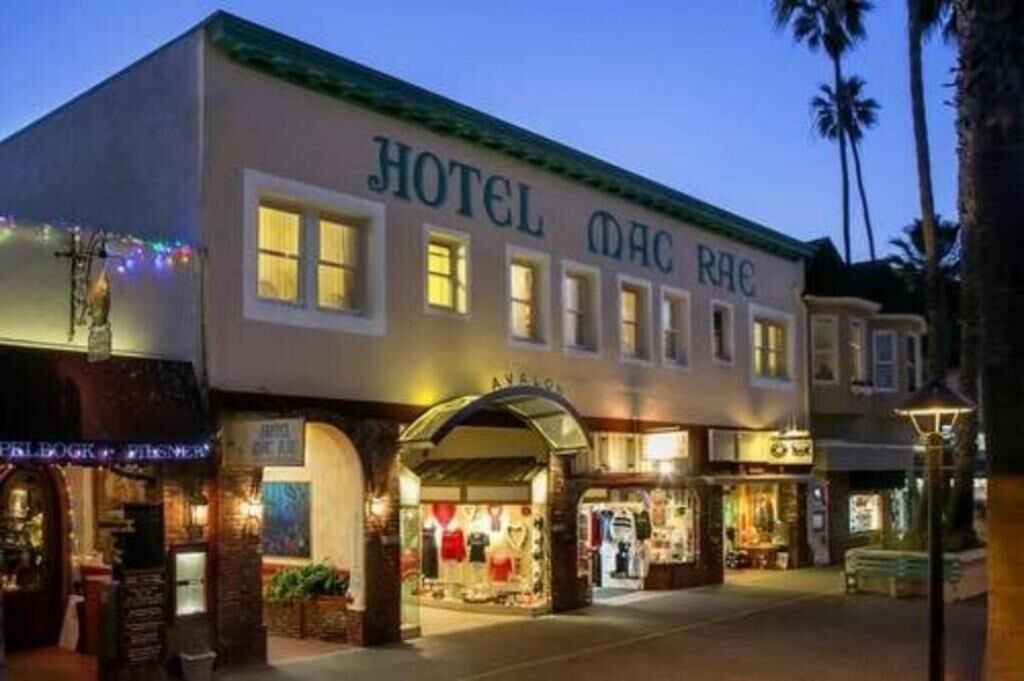 A hotel with a classic facade, multiple storefronts at the ground level, and a well-lit entrance.