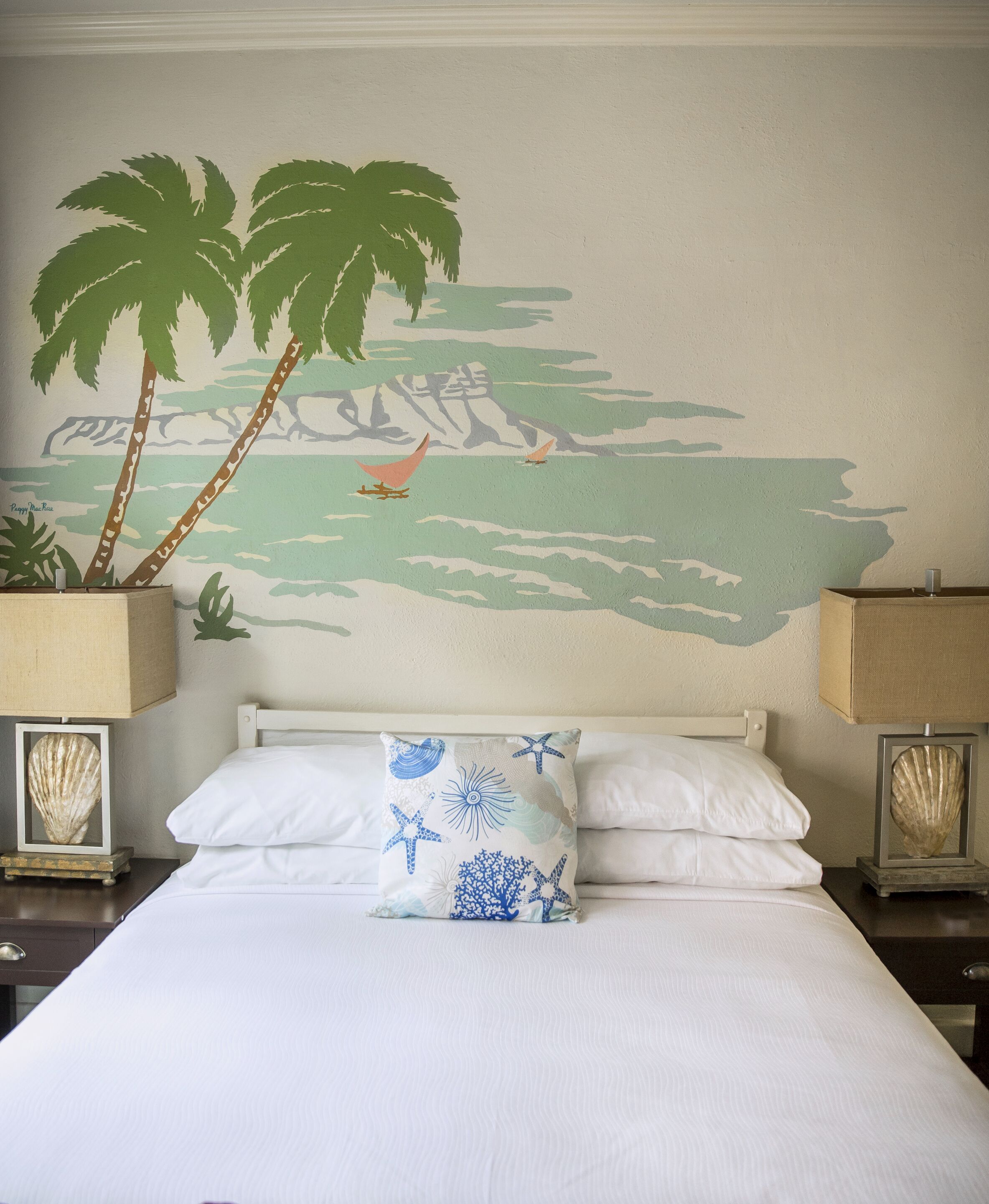 Une chambre d’hôtel avec un lit, deux tables de chevet, une fresque murale et une lampe de chevet.