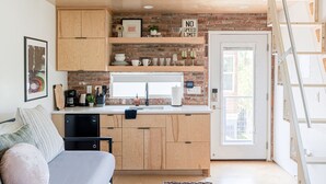 Una cucina compatta con mobili in legno, forno integrato e parete di fondo in mattoni.