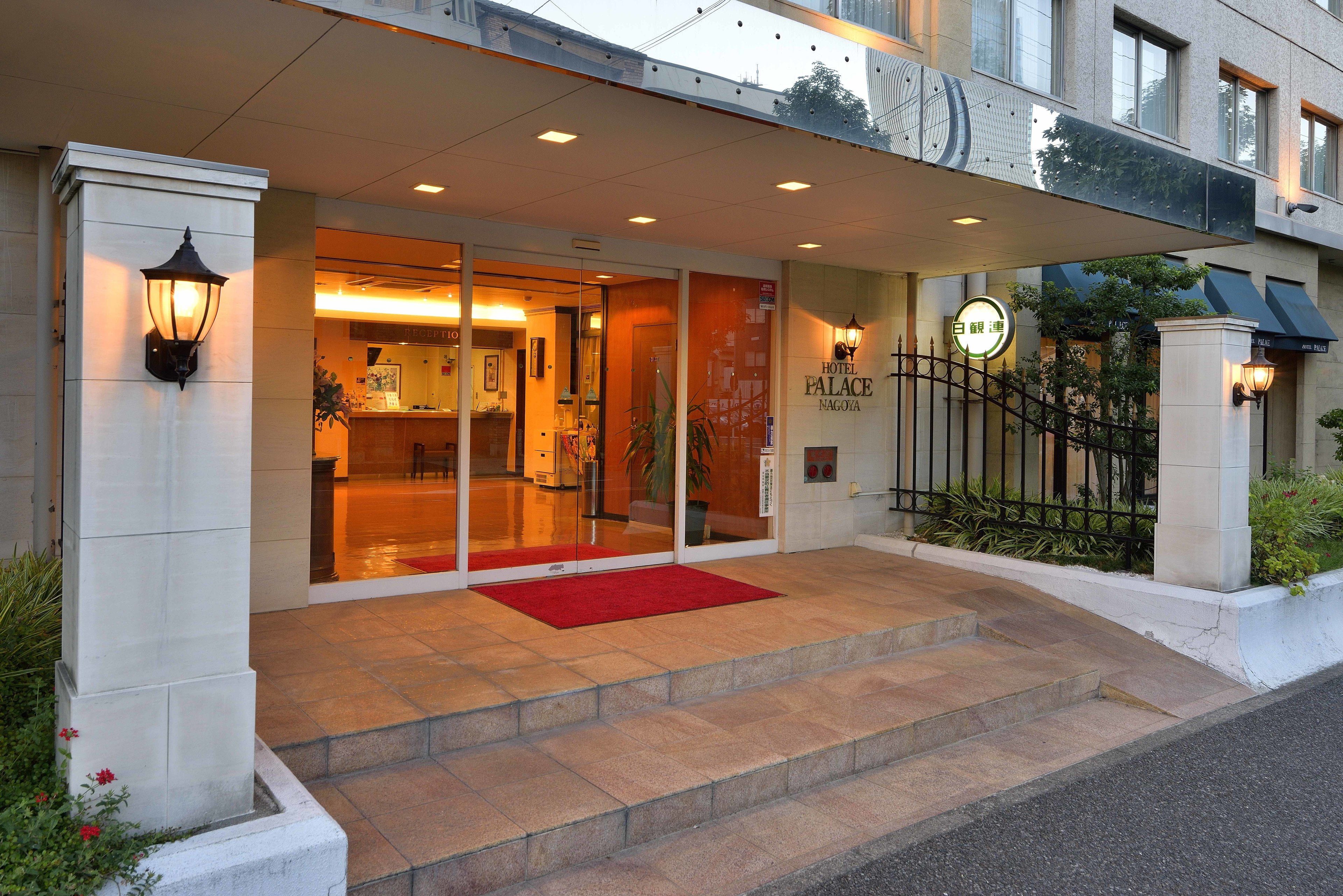A hotel entrance with a red carpet, glass doors, and a sign reading "Hotel Palace Nagoya".