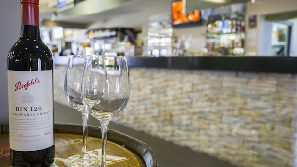 A wine bottle labeled 'Penfolds Bin 128 Coonawarra Shiraz' and two empty wine glasses on a barrel. - Tenterfield Tavern and Motor Inn (Tenterfield)