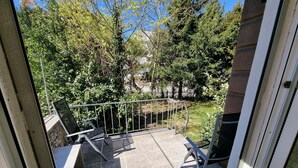 A balcony with a metal railing, a chair, and a tiled floor.
