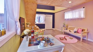 Un cuarto acogedor con techo de madera, una mesa de comedor con comida servida, un sofá y una ventana con cortinas.