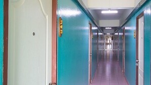 A long, narrow hallway with teal walls and a white door at the end. - P Apartment Nonthaburi (Nonthaburi)