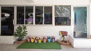 A building entrance with a welcome mat, potted plants, and a signboard. - P Apartment Nonthaburi (Nonthaburi)