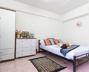 A bedroom with a bed, a dresser, a lamp, and a clock on the wall. - P Apartment Nonthaburi (Nonthaburi)