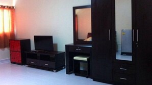 A room with a dark wooden wardrobe, a red cabinet, a television, and a small table. - T9 Muang Thong Thani Condo (Pak Kret)