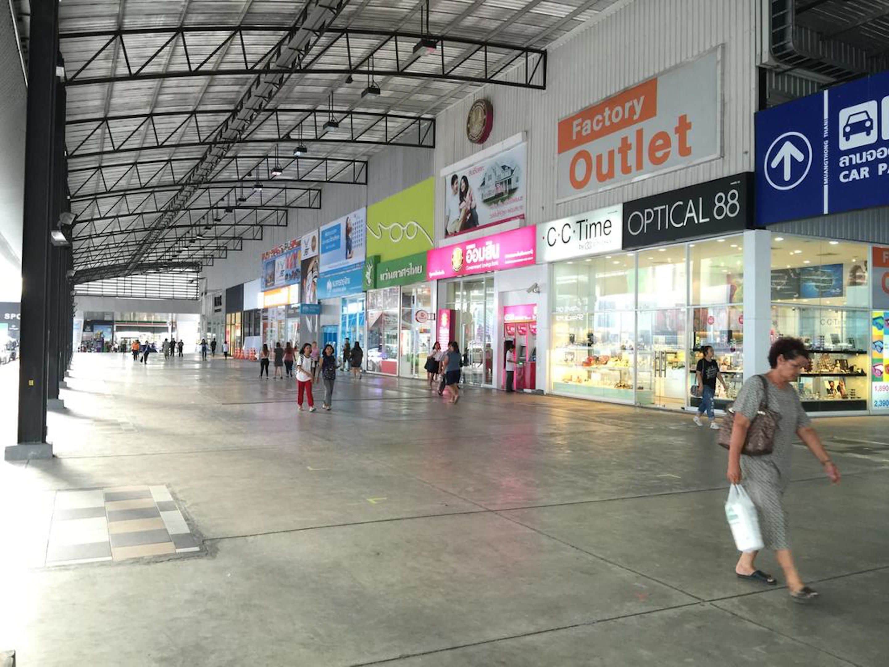 A spacious indoor shopping area with various stores, including a Factory Outlet and Optical 88.