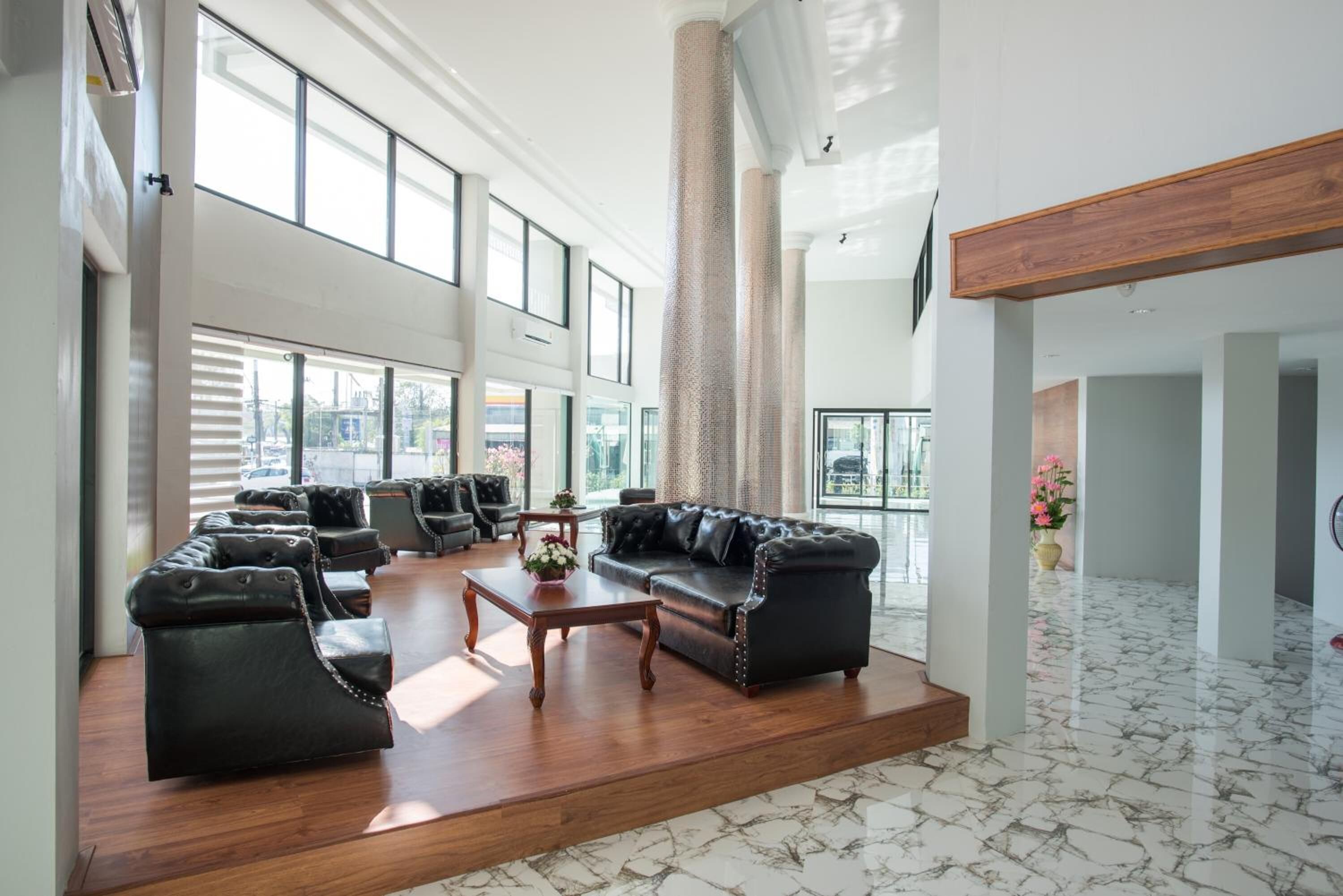 A spacious lobby with leather sofas, a wooden coffee table, and large windows offering views of the outside.