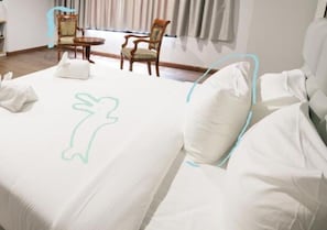 A hotel room with a neatly made bed, two chairs, and a small table.