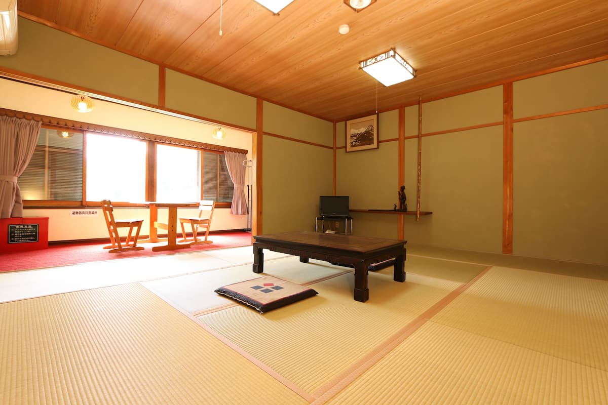 A tatami mat room with a low wooden table, a television, and a traditional Japanese cabinet.