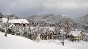 En snötäckt bergsby med traditionella byggnader, inklusive en chalet och ett trähus.