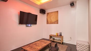 A modern living room with a flat-screen TV, a wooden coffee table, and a small side table with decorative items.