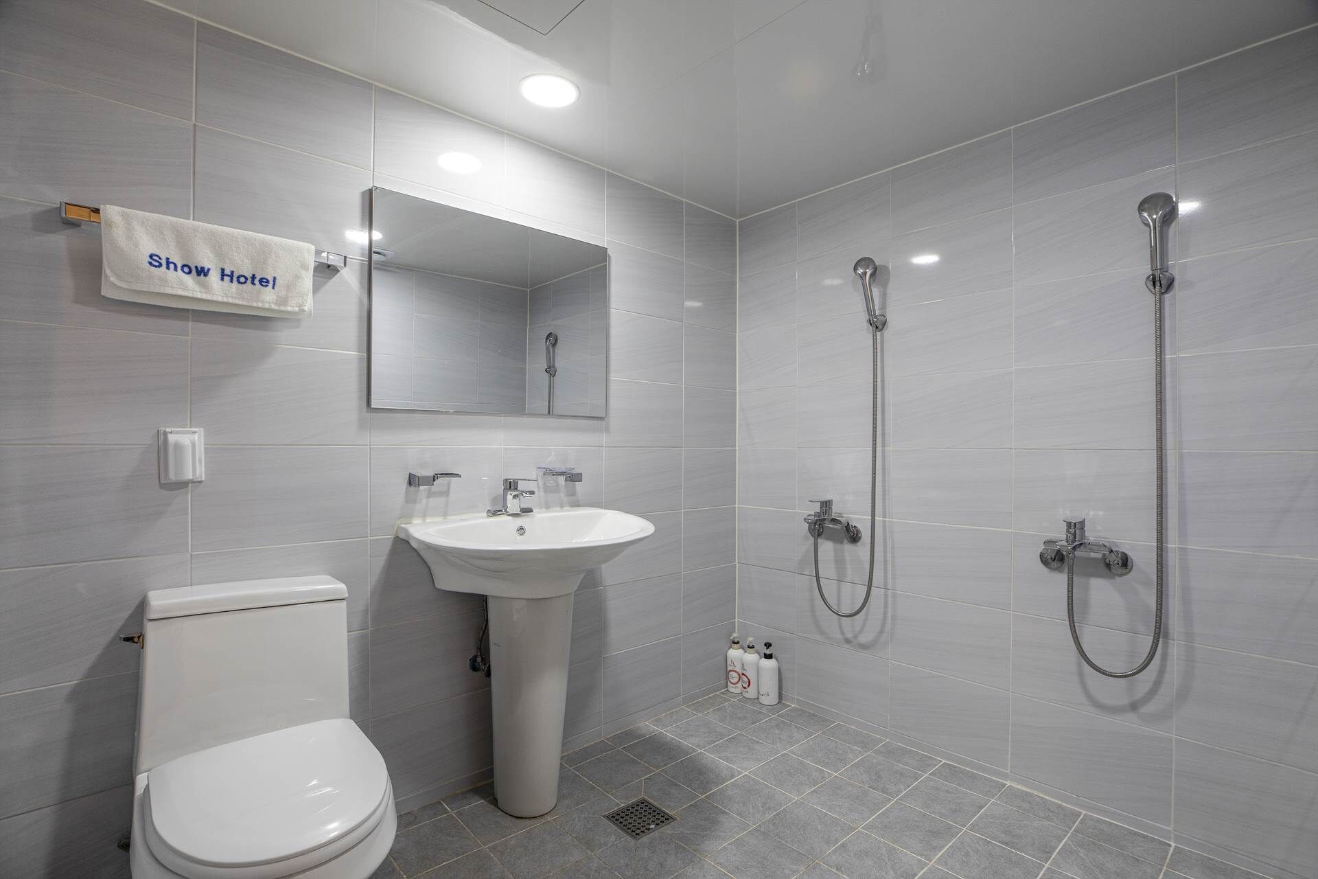 Een moderne badkamer met toilet, wastafel en twee douchekoppen.