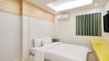 A modern bedroom with a bed, a yellow vanity, an air conditioning unit, and a green curtain.