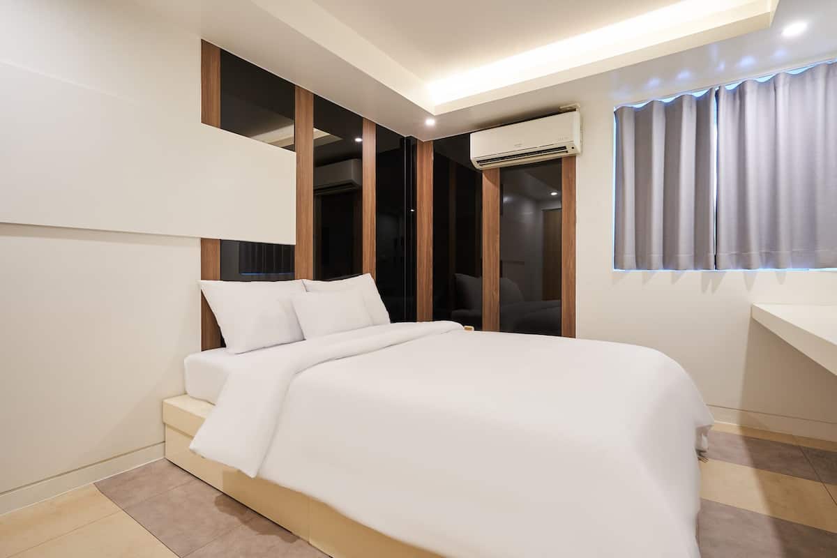 A modern bedroom with a bed, built-in wardrobe, and an air conditioning unit.