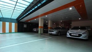 Un aparcamiento de varios niveles, con plazas delimitadas y un diseño moderno con detalles en naranja.