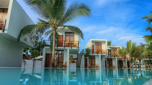 A modern resort with a clear pool, multiple-story buildings, and palm trees. - Arugambay Roccos (Arugam Bay)