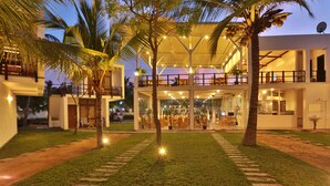 A two-story building with a covered outdoor seating area, palm trees, and a well-maintained lawn. - Arugambay Roccos (Arugam Bay)