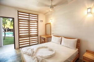 Un dormitorio con cama, cabecero de madera, mesita de noche, escritorio y espejo.