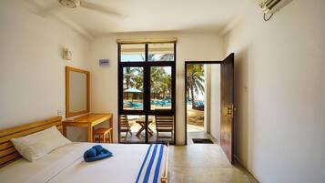Habitación de hotel con cama, escritorio y vistas a un espacio exterior con sillas y sombrillas.