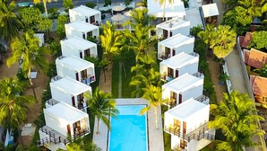 An aerial view of a resort with multiple white buildings, a central swimming pool, and surrounding palm trees. - Arugambay Roccos (Arugam Bay)