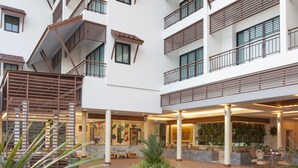 A modern hotel with a central pool, multiple balconies, and indoor seating areas. - RK Riverside Resort & Spa (Sam Phran)
