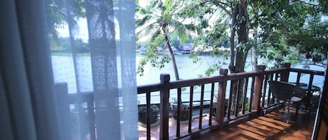 A wooden deck with a railing overlooking a body of water and trees.