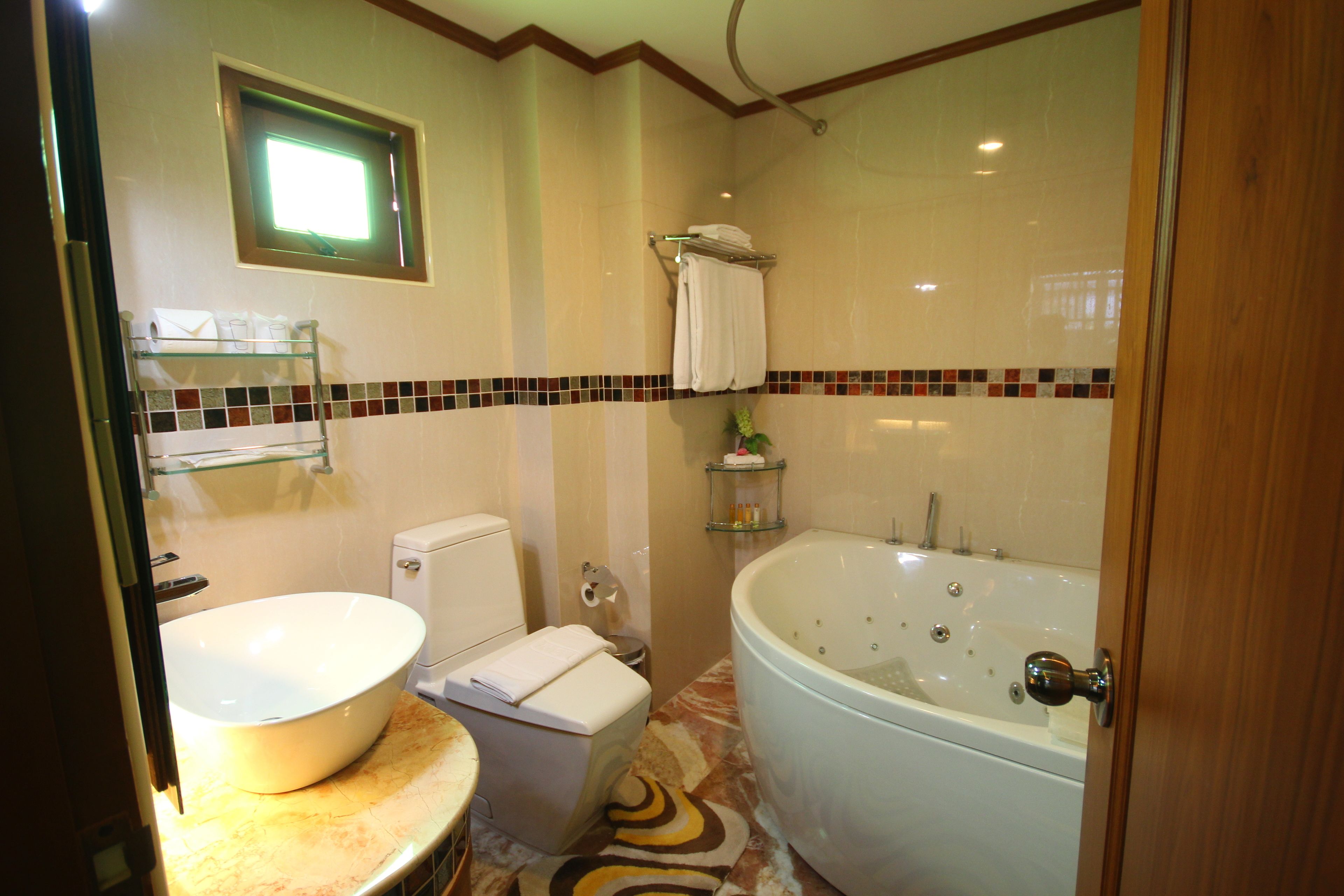 A bathroom with a large bathtub, a toilet, and a sink.