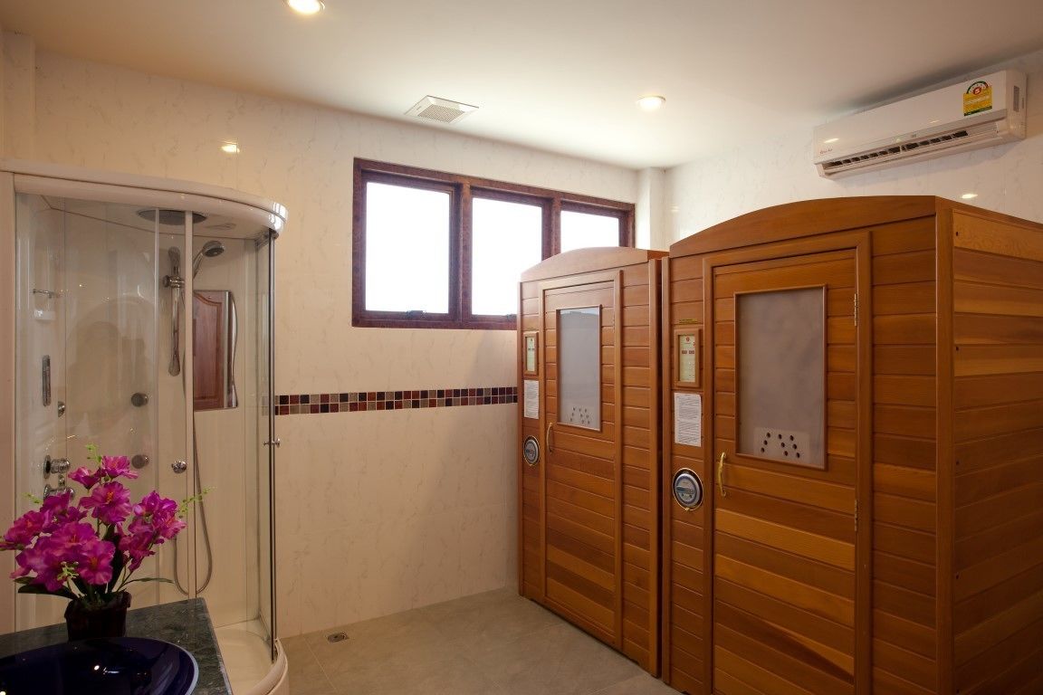 A bathroom with a glass-enclosed shower, wooden cabinets, and a window.