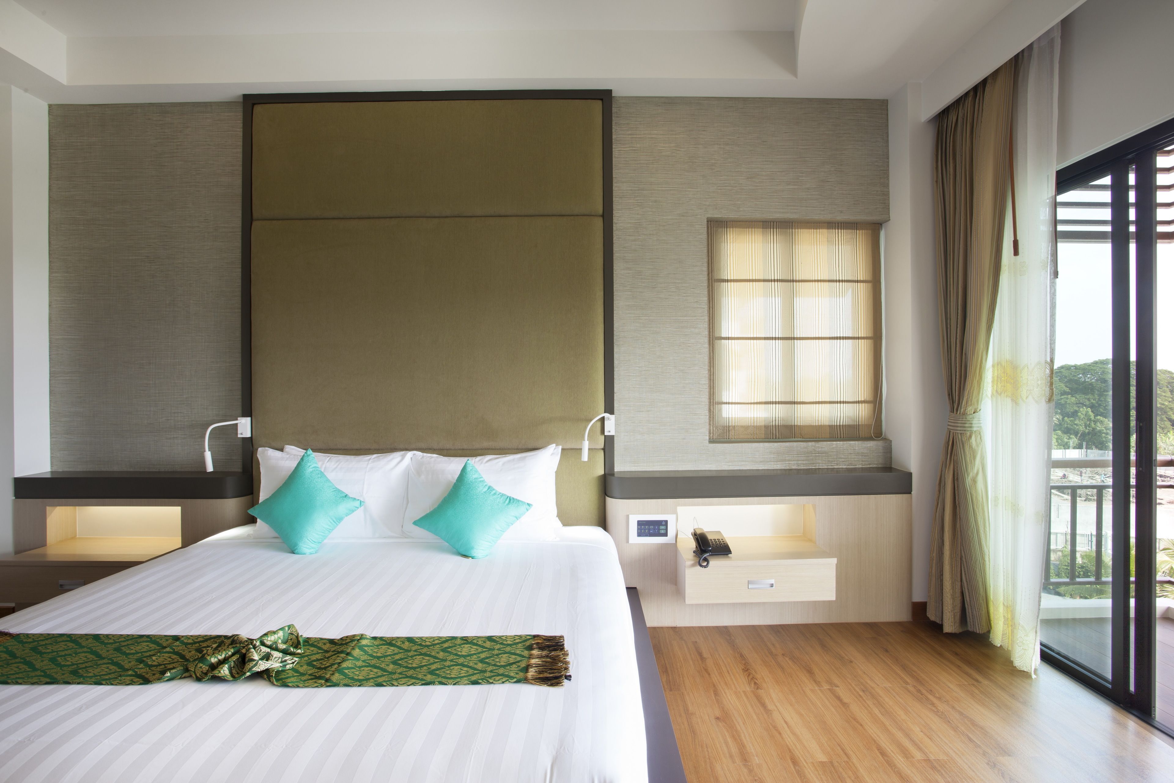 Una habitación de hotel moderna con una cama grande, mesitas de noche, un ventanal y vistas al exterior.