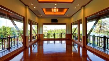 A spacious room with large windows, a wooden floor, and a ceiling with recessed lighting.