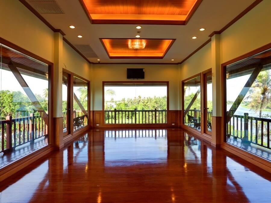 A spacious room with large windows, a wooden floor, and a ceiling with recessed lighting.