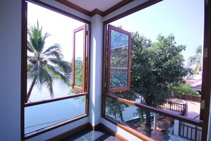 A corner room with large windows overlooking a balcony and palm trees.