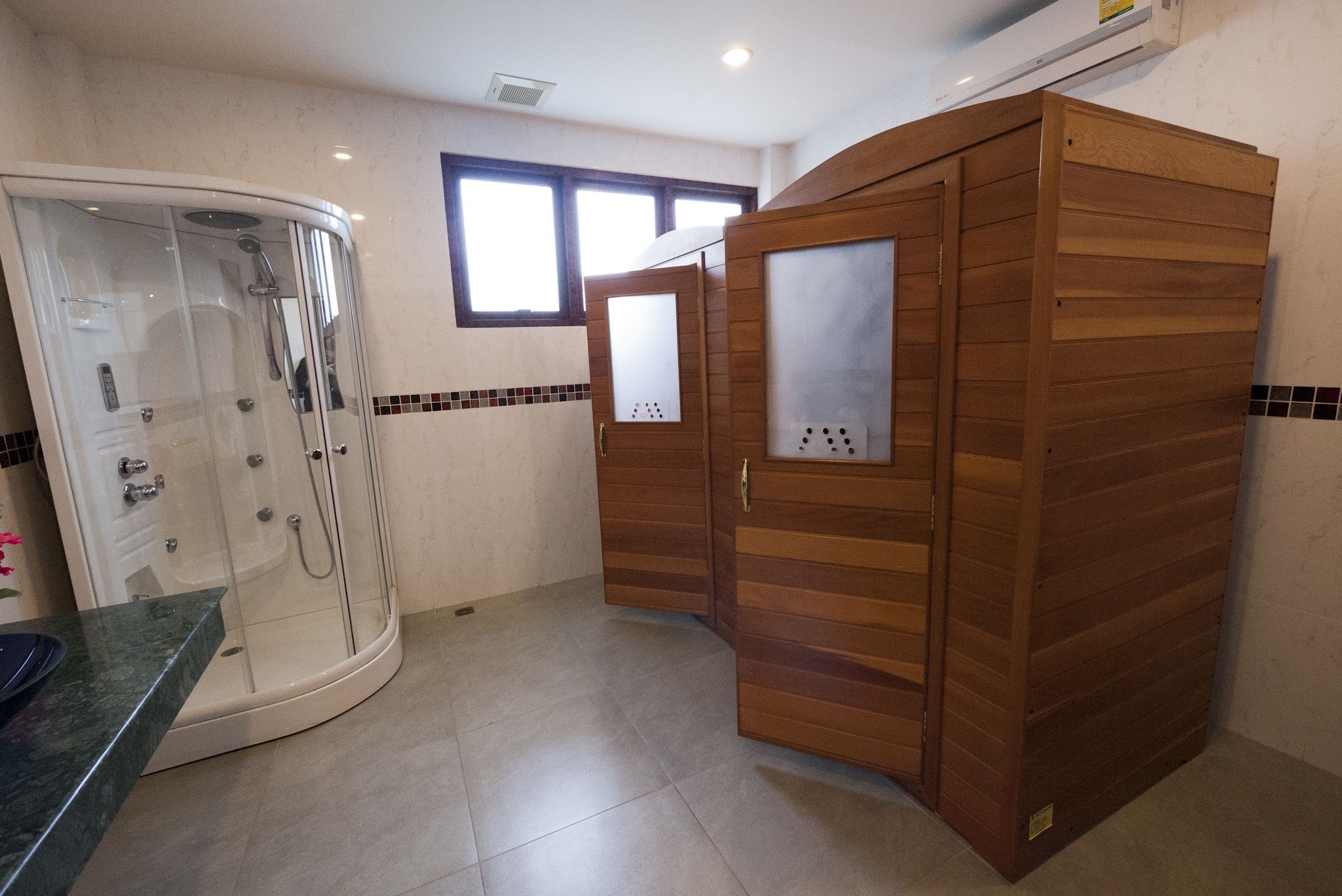 Un baño con ducha de vidrio, muebles de madera y piso de baldosas.