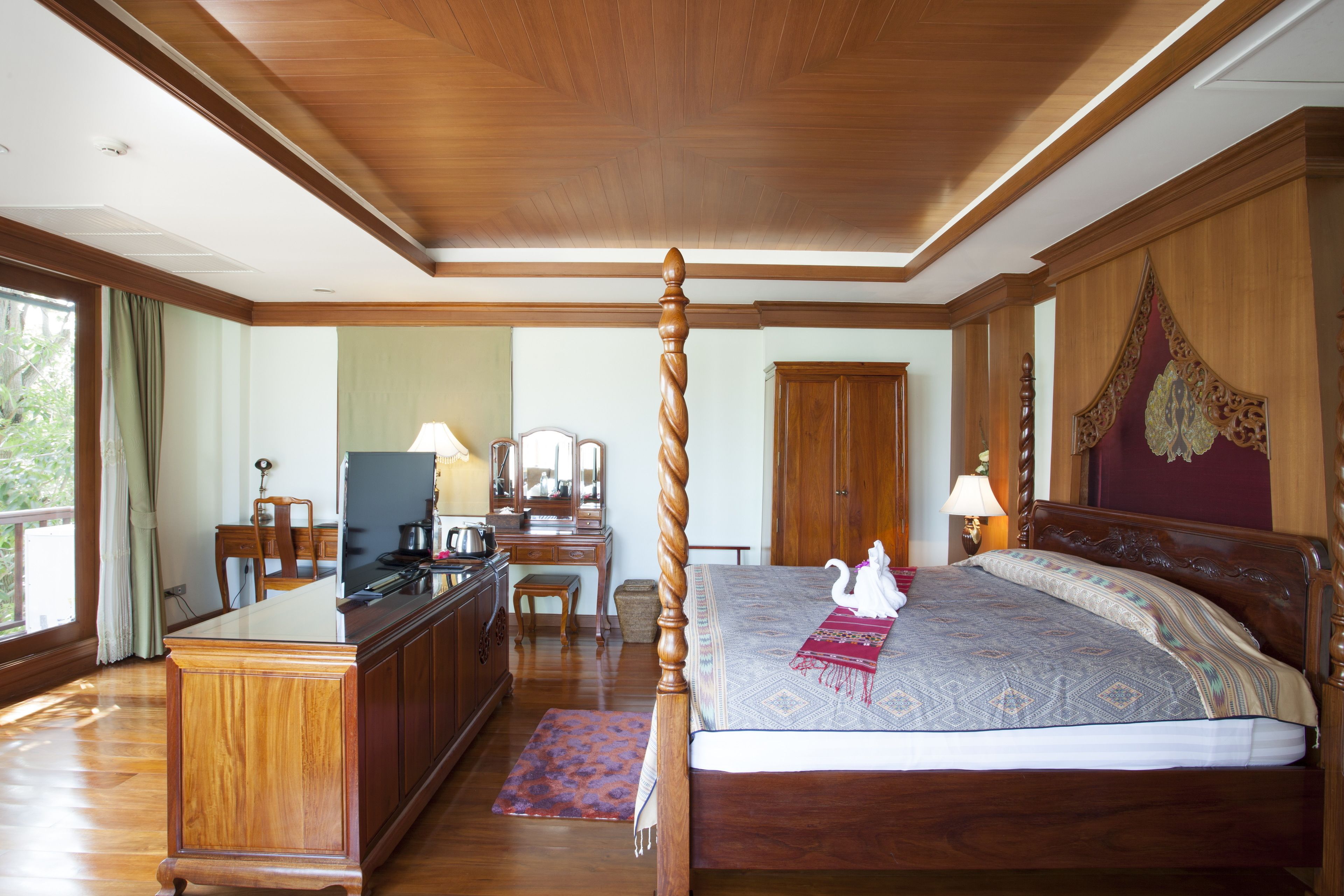 Um quarto espaçoso com uma cama grande, móveis de madeira e uma escrivaninha com uma cadeira.