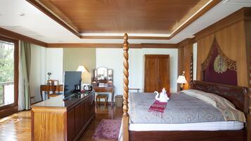 A spacious bedroom with a large bed, wooden furniture, and a desk with a chair.