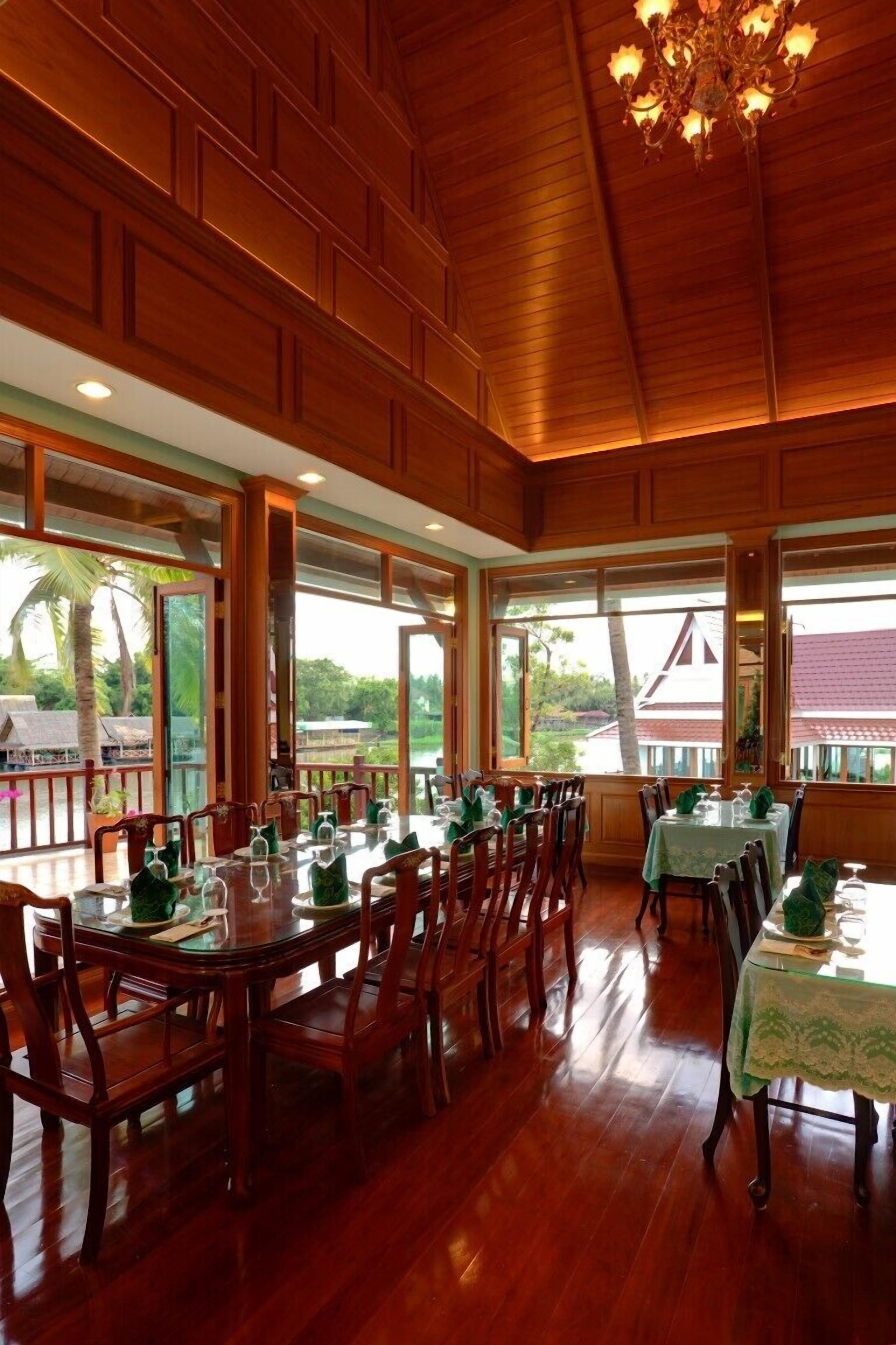 A restaurant with wooden paneling, large windows, and a view of palm trees.