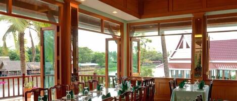 A restaurant with wooden paneling, large windows, and a view of palm trees.