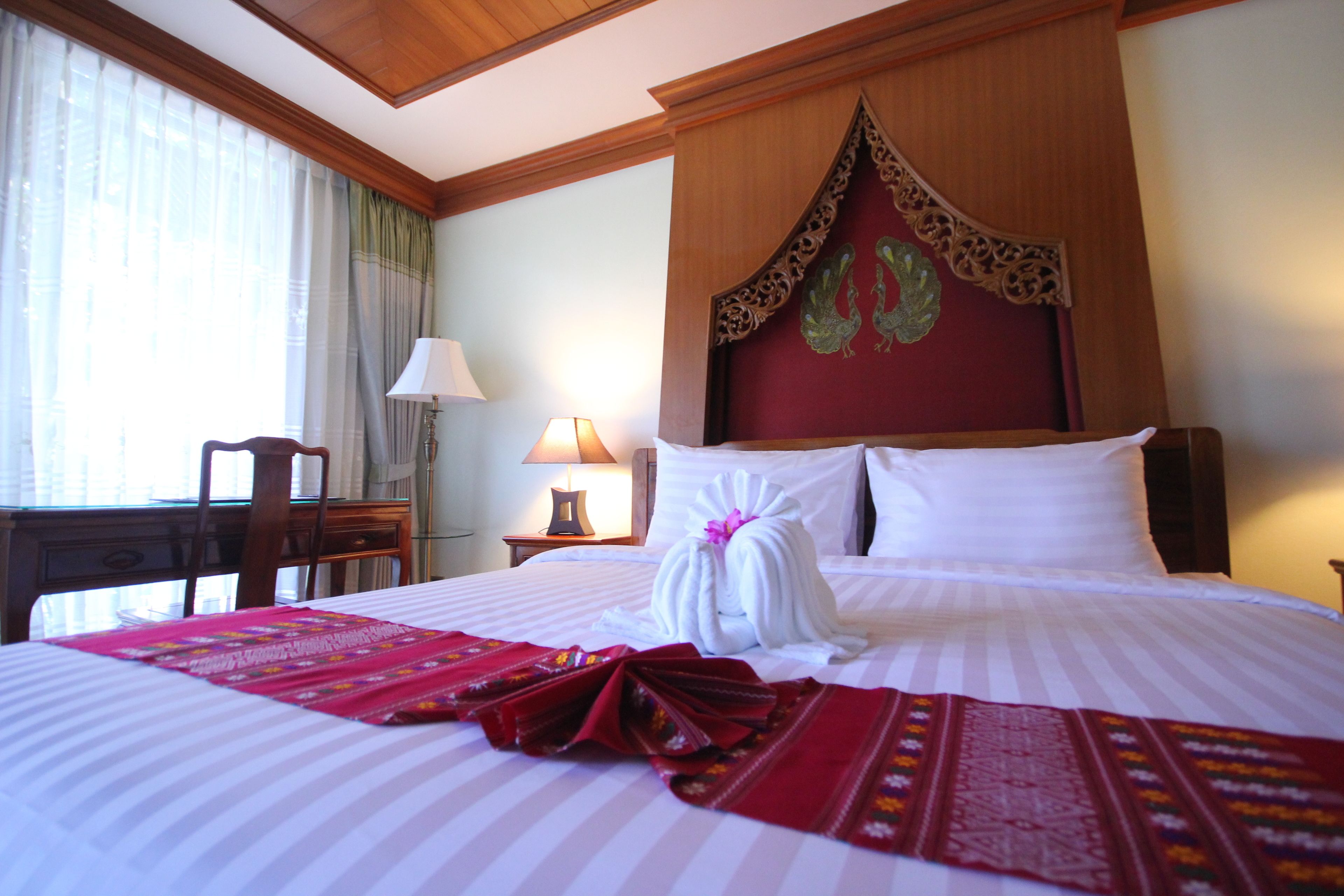 Una habitación de hotel con una cama bien hecha, un escritorio y una lámpara.