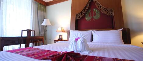 Una habitación de hotel con una cama bien hecha, un escritorio y una lámpara.