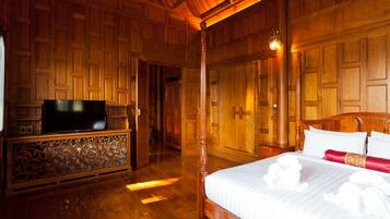 A wooden-paneled room with a bed, a TV on a stand, and a hallway leading to another room.