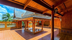 A covered outdoor area with a tiled floor, wooden beams, and a metal roof structure. - RK Riverside Resort & Spa (Sam Phran)