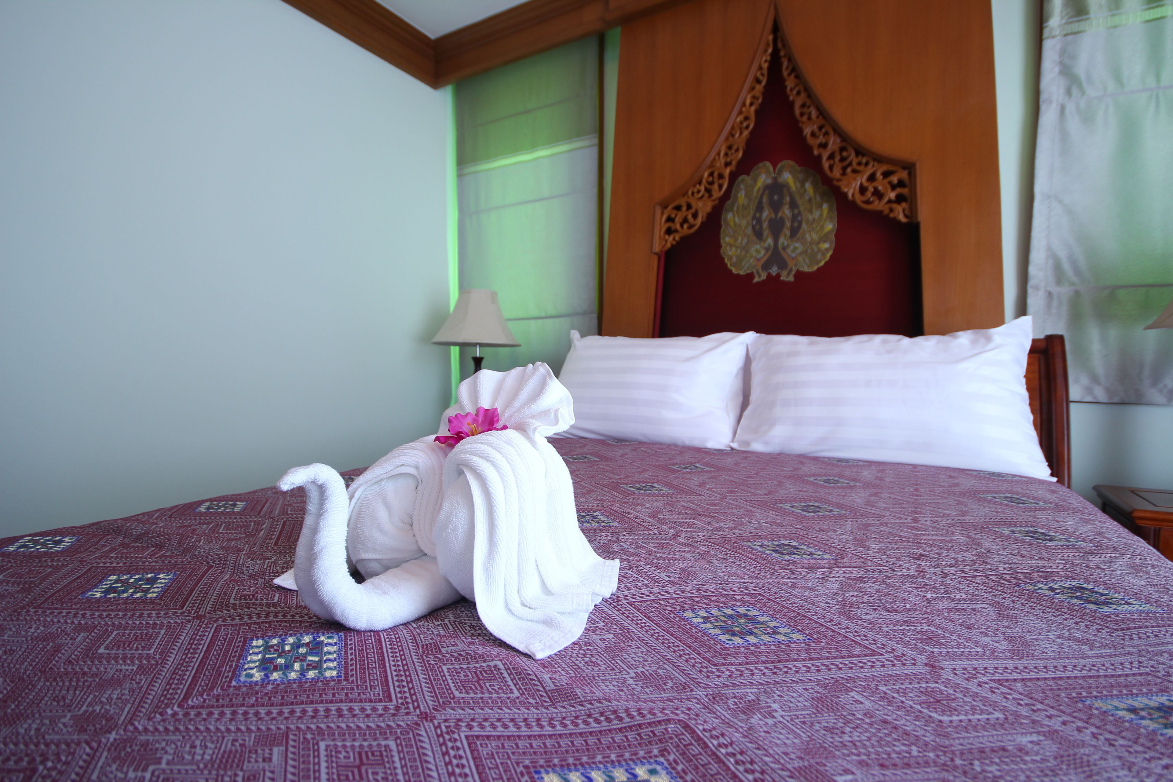 A hotel room with a bed, a nightstand, a lamp, and a decorative headboard.