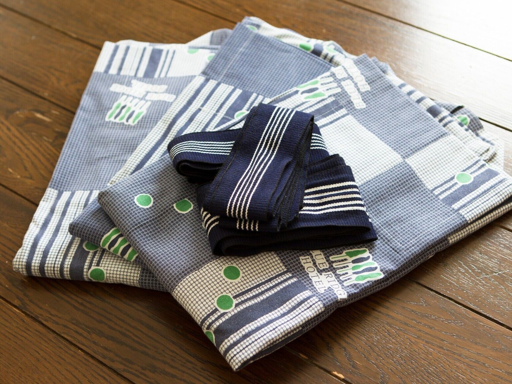 A neatly folded bedspread with a striped pattern and green accents on a wooden floor.